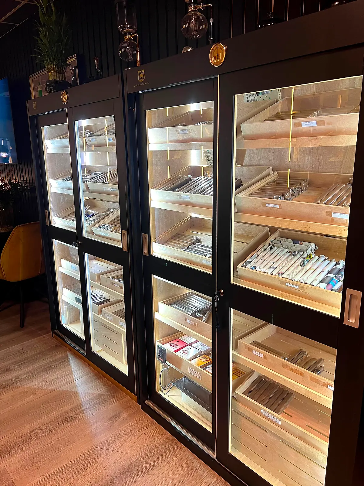 Glass-fronted humidor cabinets stocked with premium cigars